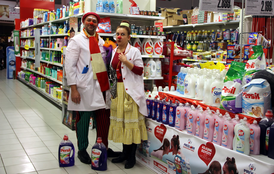 Két bohócdoktor egy üzletben mosószereket reklámoz.